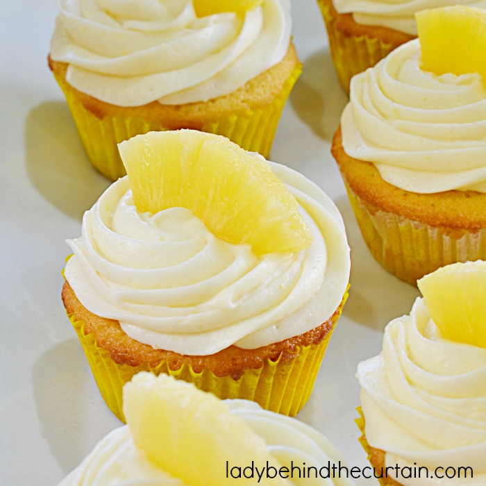 Pineapple Cupcakes | A layer of pineapple tucked in the middle with a cherry surprise at the bottom all topped with a cream cheese frosting.