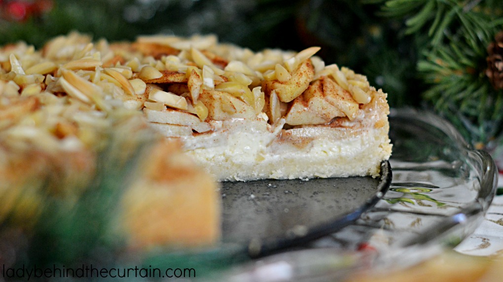 Apple Danish Cheesecake | This cheesecake starts with a delightful almond crust a thin layer of cheesecake all topped with tart apple rolled in a brown sugar cinnamon mixture and almonds.